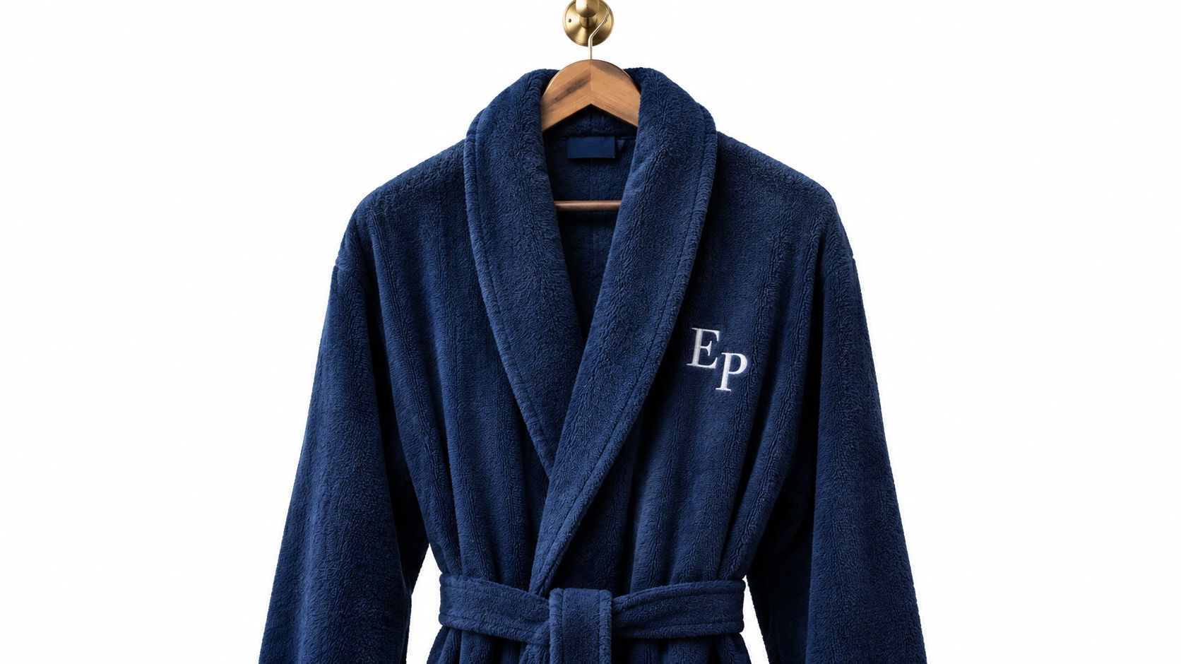 A plush navy blue bath robe with white embroidered initials Ep hanging on a wooden hanger.